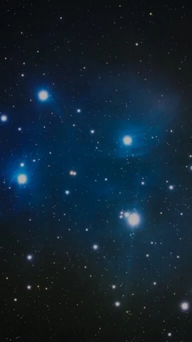 Pleiades star cluster (M45) astrophotography showing bright blue stars surrounded by faint reflection nebula in the Taurus constellation.